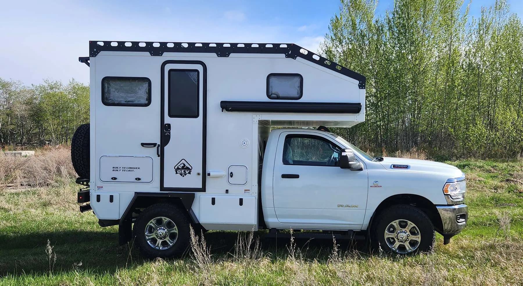 2024 OEV Hudson Bay integrated hard side camper installed on a white Ram truck, side view. Truck not included.