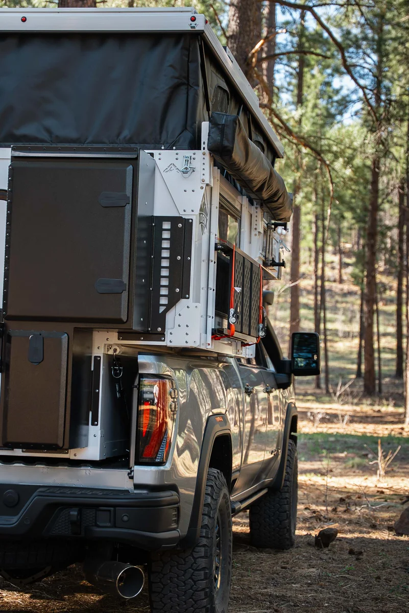 Back Country 6.85 driver-side rear panel with storage boxes, MOLLE rack, and Truma connections, pop-up roof deployed