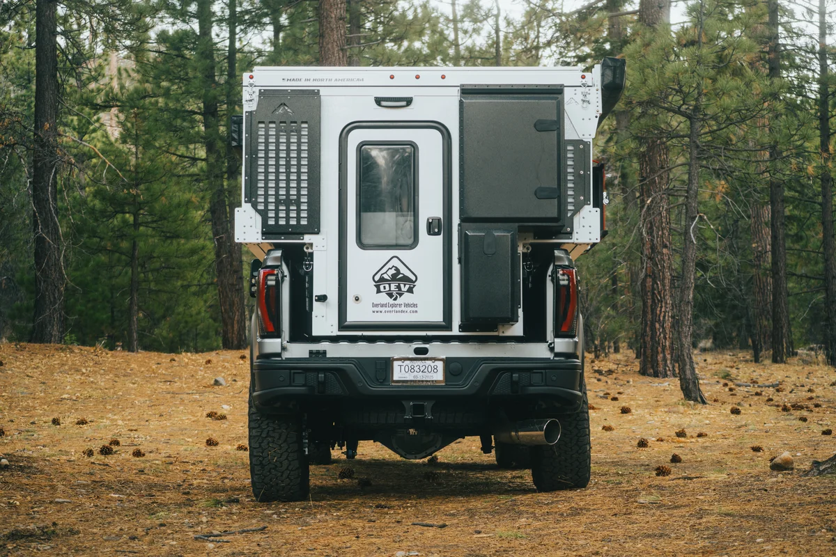 Back Country 6.85 straight rear view showing entry door, MOLLE panel, roof closed in pine forest