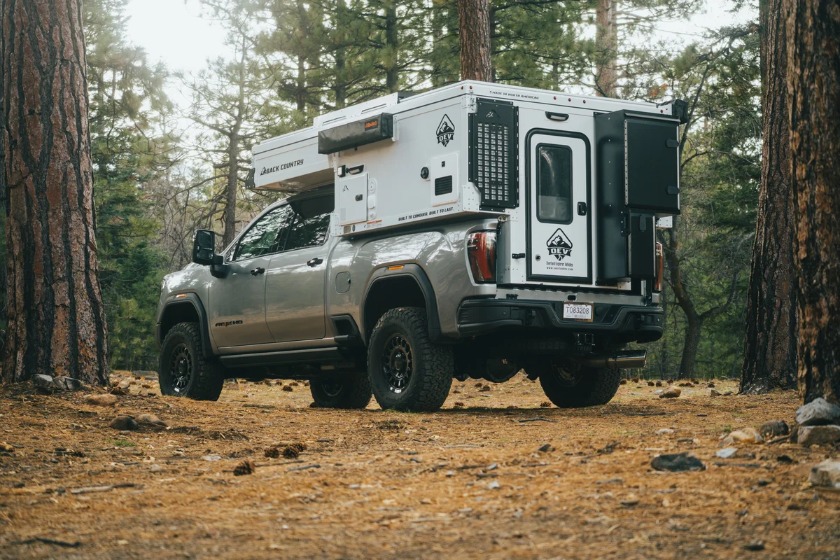 Back Country 6.85 driver-side rear three-quarter with pop-up closed on GMC AT4X in pine forest