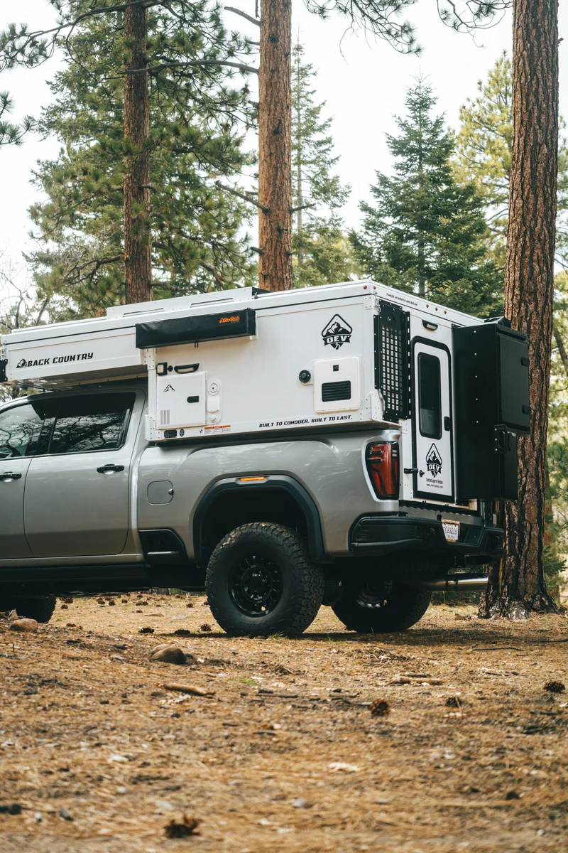 Back Country 6.85 passenger side profile with Back Country badge and roof closed in pine forest