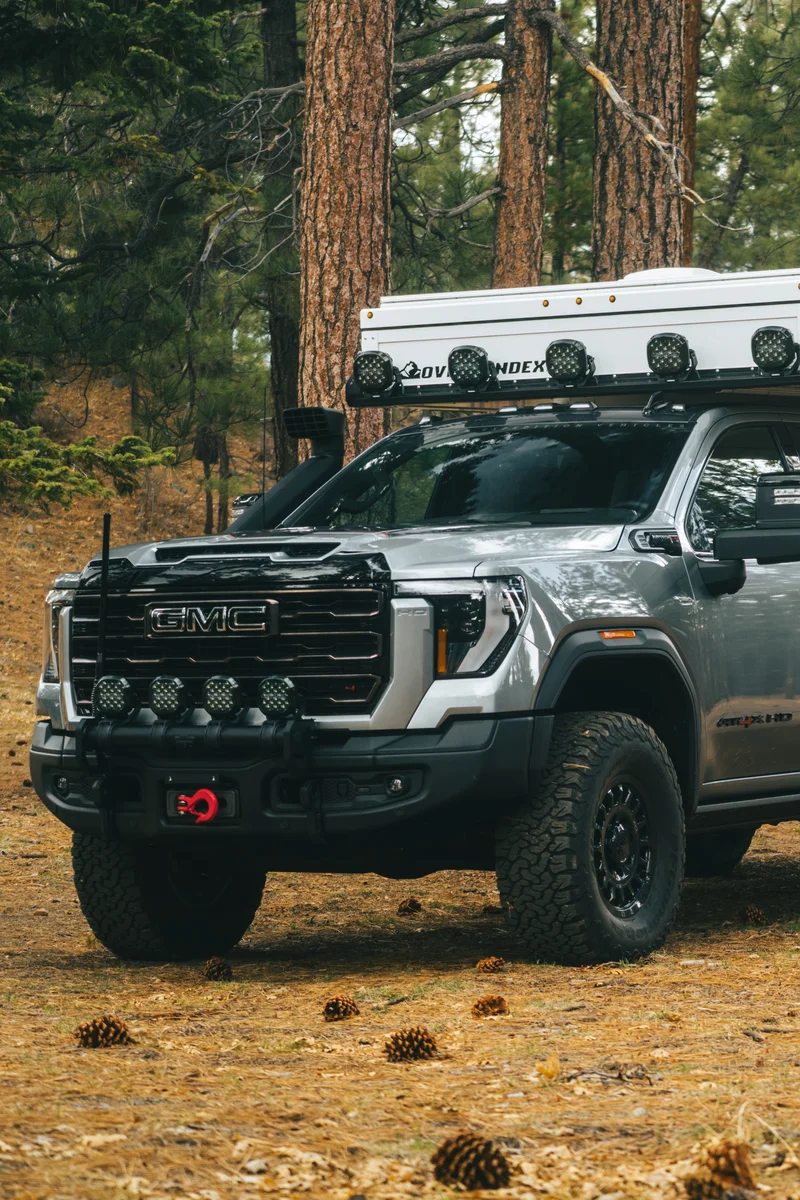 Back Country 6.85 front three-quarter on GMC with light bar, winch, and grille guard in pine forest
