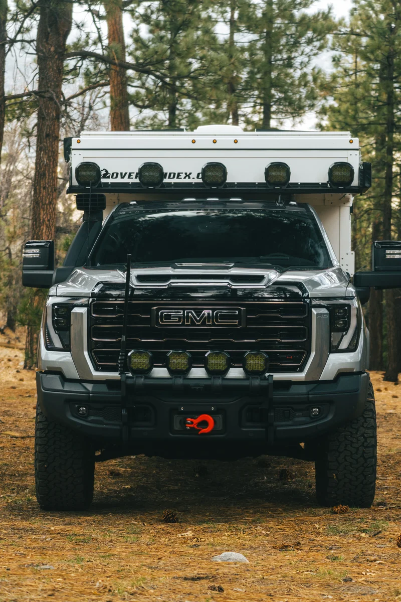 Back Country 6.85 straight front view showing GMC grille, winch, OEV light bar, and camper above