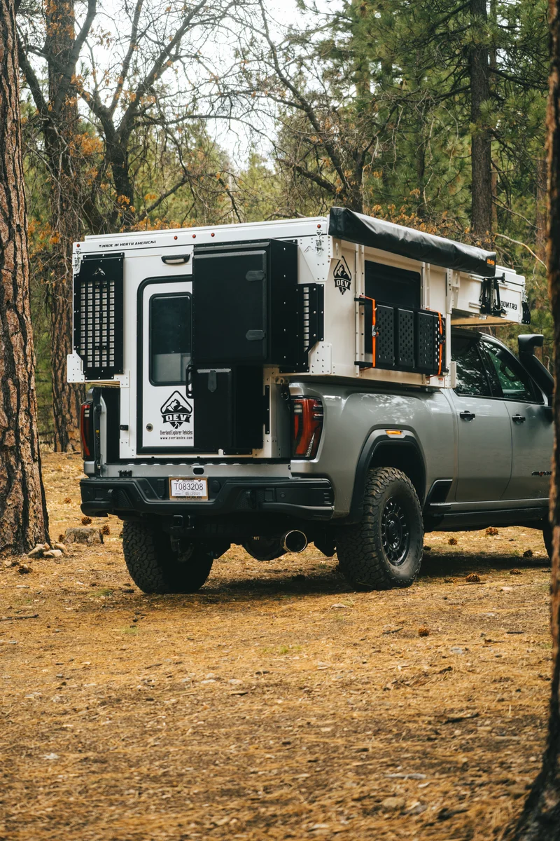Back Country 6.85 rear three-quarter portrait with pop-up roof open, entry door open, and MOLLE panel