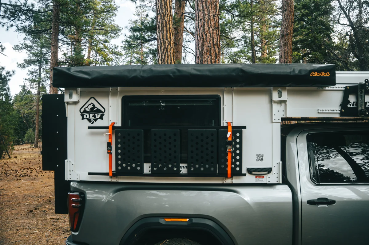 Back Country 6.85 passenger side close-up with OEV badge, Alu-Cab awning, and MOLLE folding steps