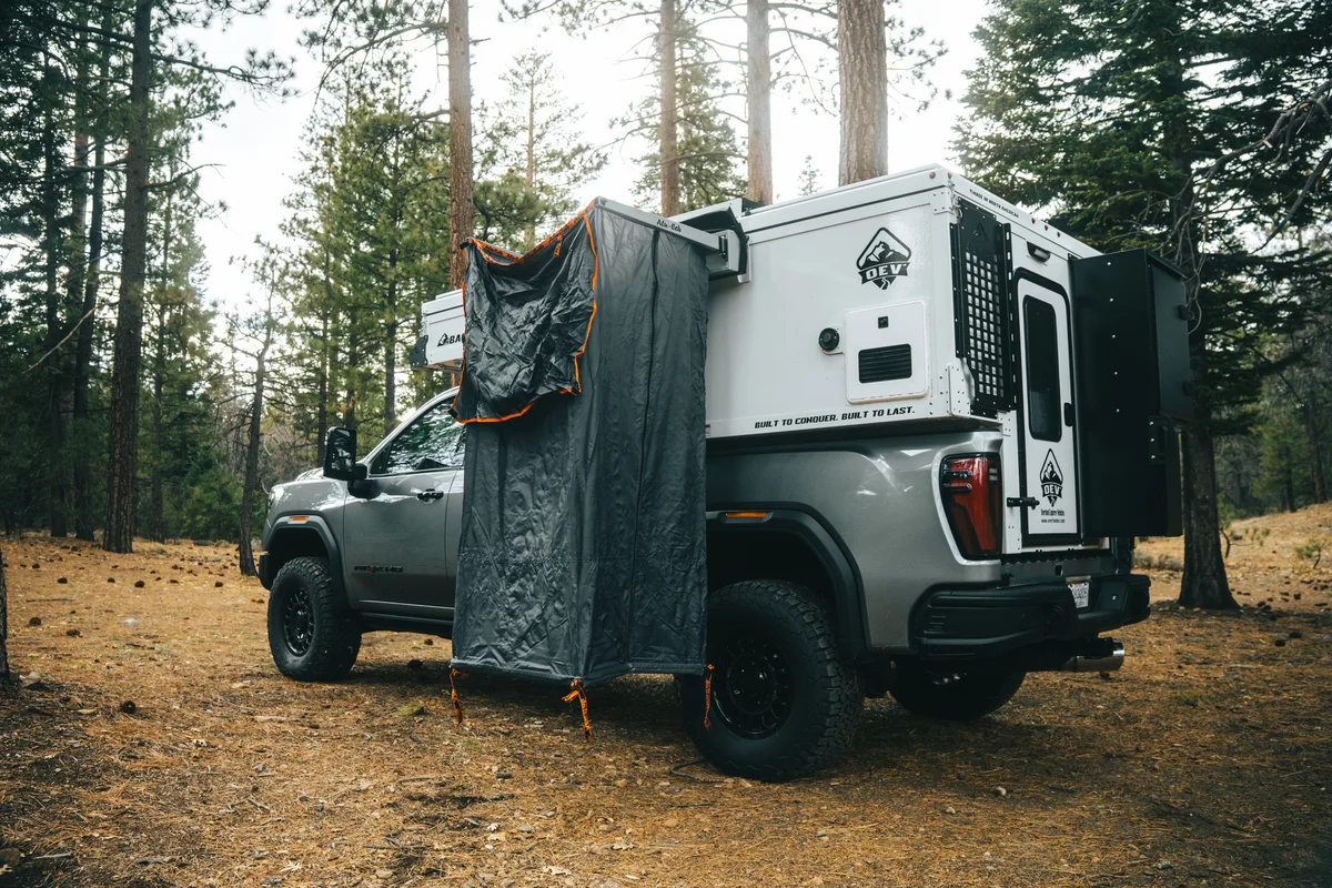 Back Country 6.85 rear three-quarter with outdoor shower enclosure deployed and 'Built to Conquer' visible