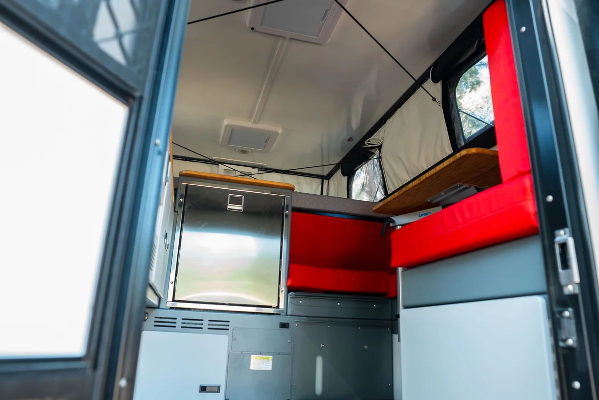 Back Country 6.85 interior from entry showing red dinette cushions, compressor fridge, and bamboo countertop