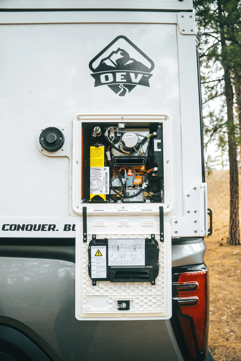 Back Country 6.85 exterior utility panel wider view with Truma heater and OEV badge above