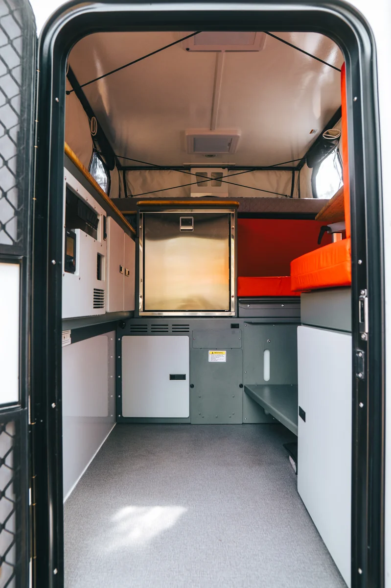 Back Country 6.85 interior from entry door showing cabinetry and red dinette in lengthwise view