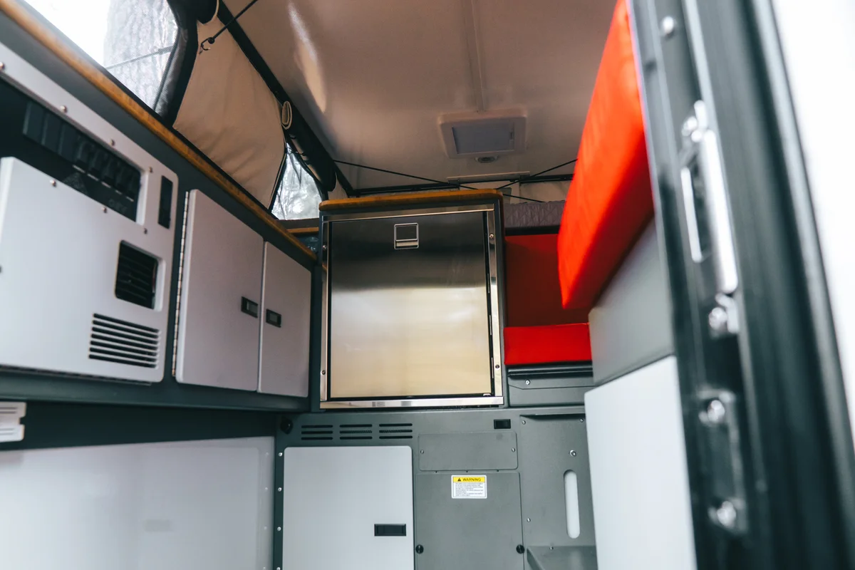 Back Country 6.85 interior wide shot showing Dometic fridge, red dinette, and cabinetry from elevated angle