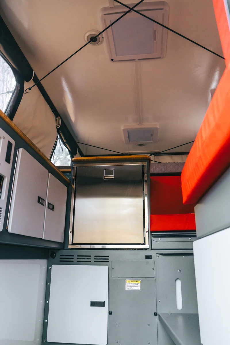 Back Country 6.85 interior portrait looking toward compressor fridge and red dinette from near entry