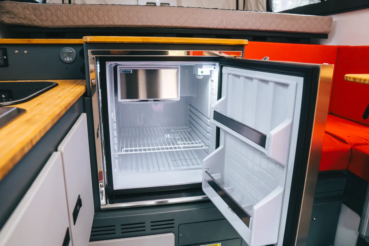 Back Country 6.85 Dometic compressor fridge open with empty lit interior and bamboo countertop above