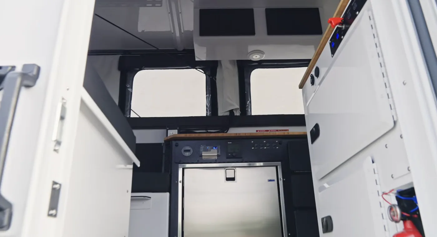 View into the Hudson Bay 6.75' from the entry door showing the stainless drawer fridge, bamboo countertop, soft-wall windows, and the air conditioner's ceiling unit