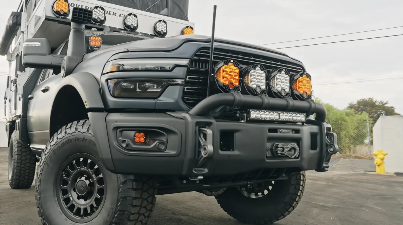 Front of the Ram 3500 AEV Prospector XL showing four round amber and white lights on the AEV bumper and five more on the OEV light bar above the cab
